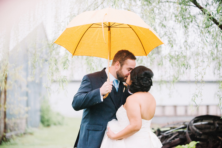 wedding couple kissing under an umbrella