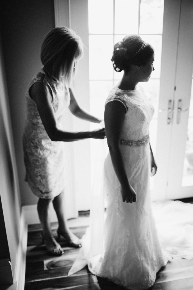 brides mom helping her into her dress