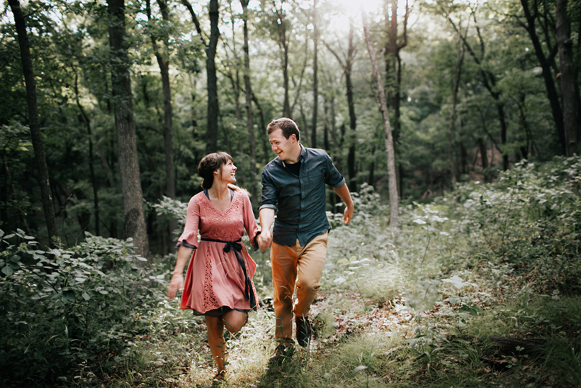 couple running in the woods at their engagement session