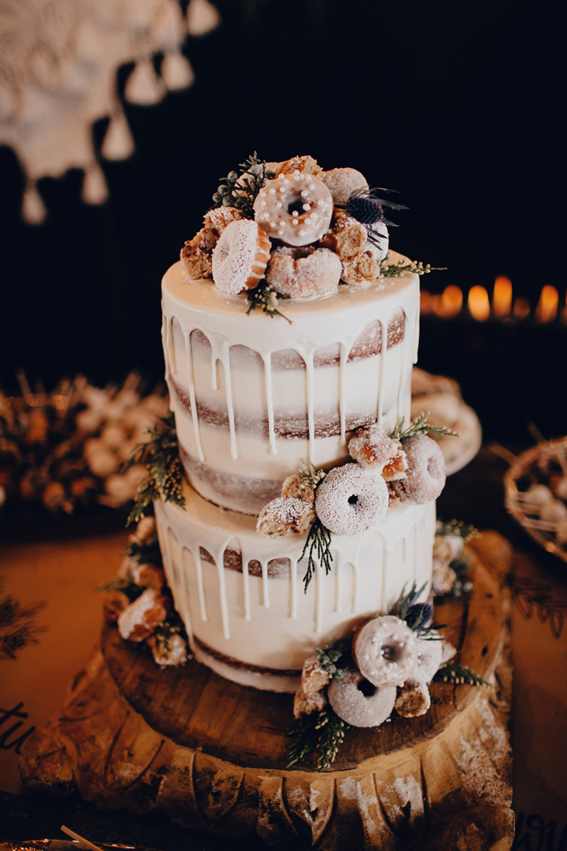 wedding naked cake topped with mini donuts and decorated with dripping icing