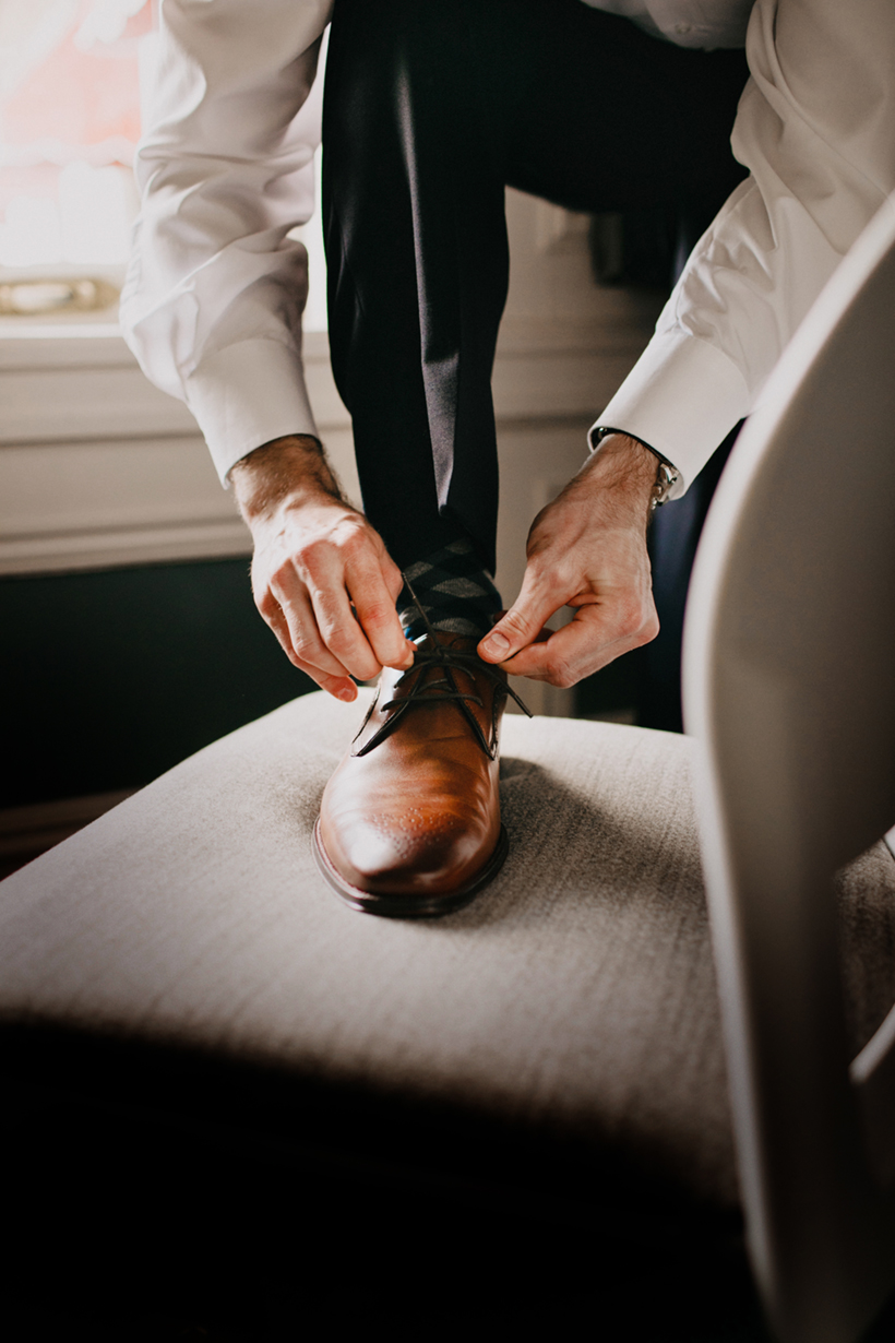 groom tying shoelaces on brown leather shoes